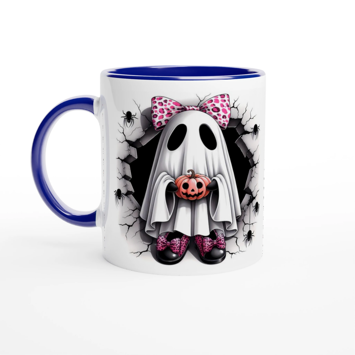 White mug with blue handle and interior, featuring a ghost with a pink spotted bow holding a jack-o’-lantern, surrounded by cracked stone and spiders