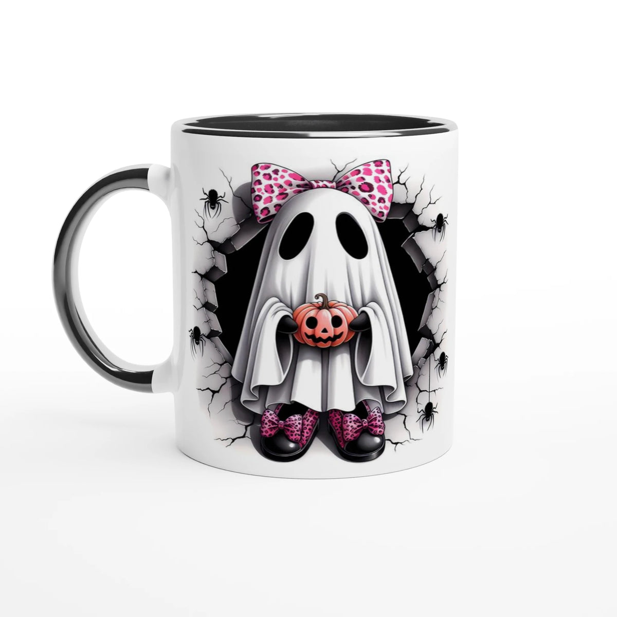 White mug with black handle and interior, featuring a ghost with a pink spotted bow holding a jack-o’-lantern, surrounded by cracked stone and spiders.