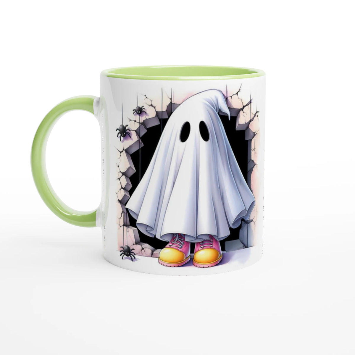 White mug with light green handle and interior, featuring a sheet ghost in pink and yellow shoes, framed by cracked stone and spiders.